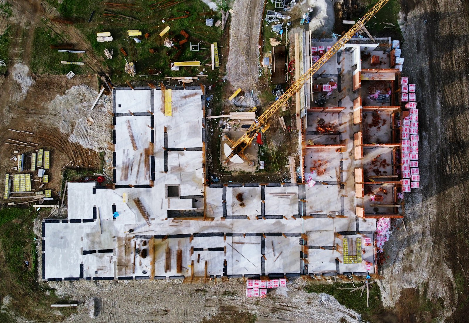 Aerial view of an active construction site with foundations and framing underway